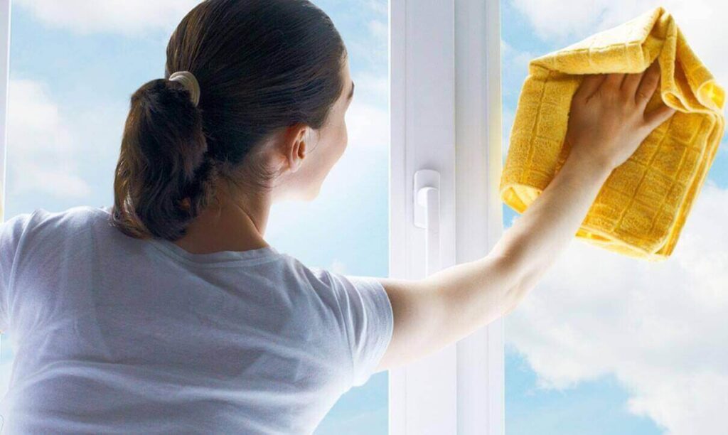 A woman from office cleaning services is wiping the window pane