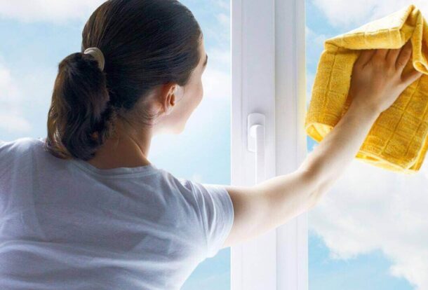 A woman from office cleaning services is wiping the window pane